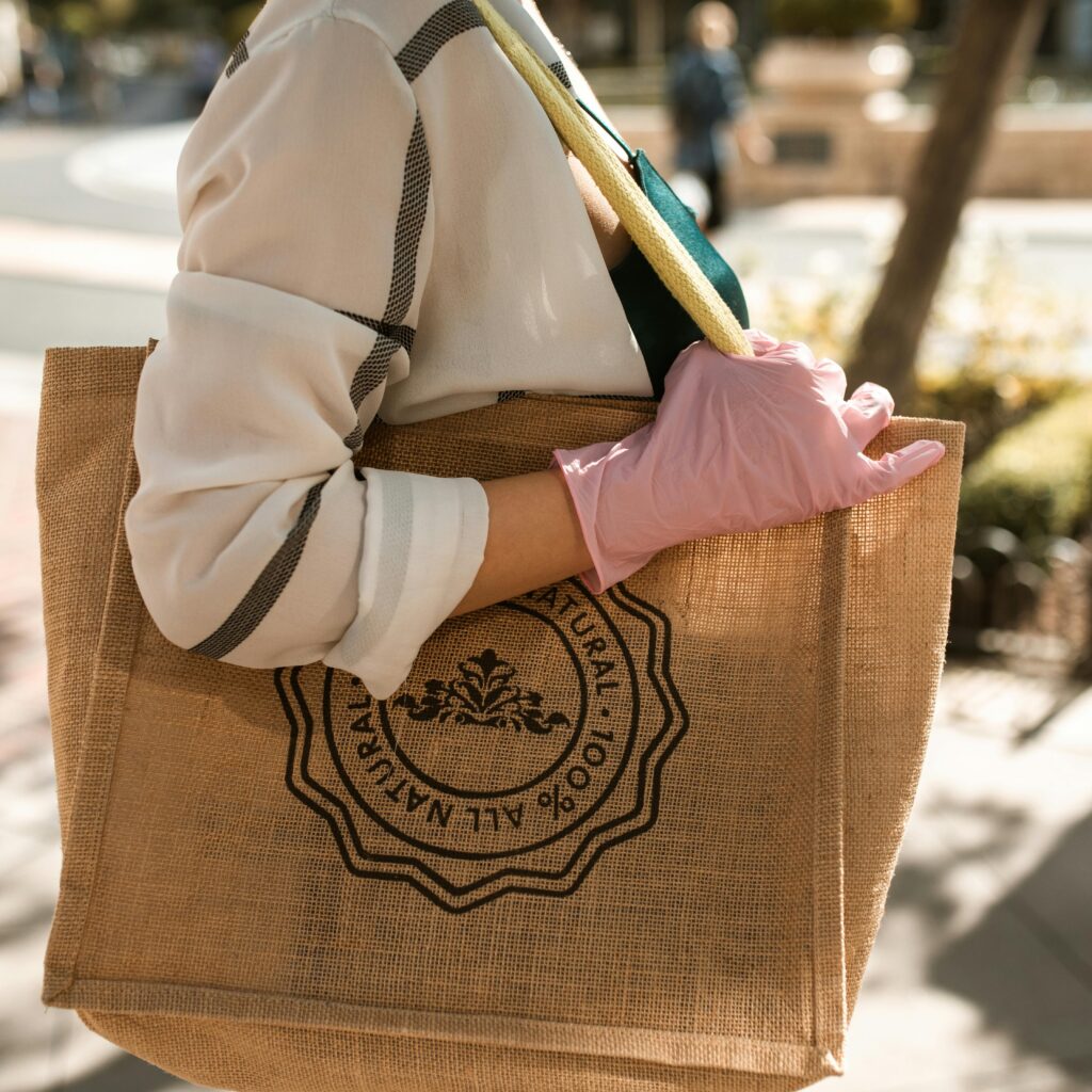 pexels-photo-5699380-5699380 Close-up of a person with a brown tote bag and pink glove, outdoors on a sunny day.